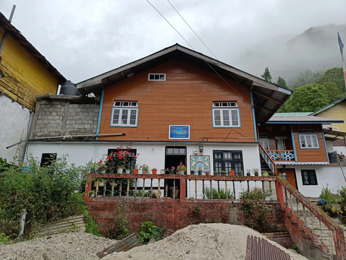 Traditional wooden homestay in Lachung village with mountain backdrop