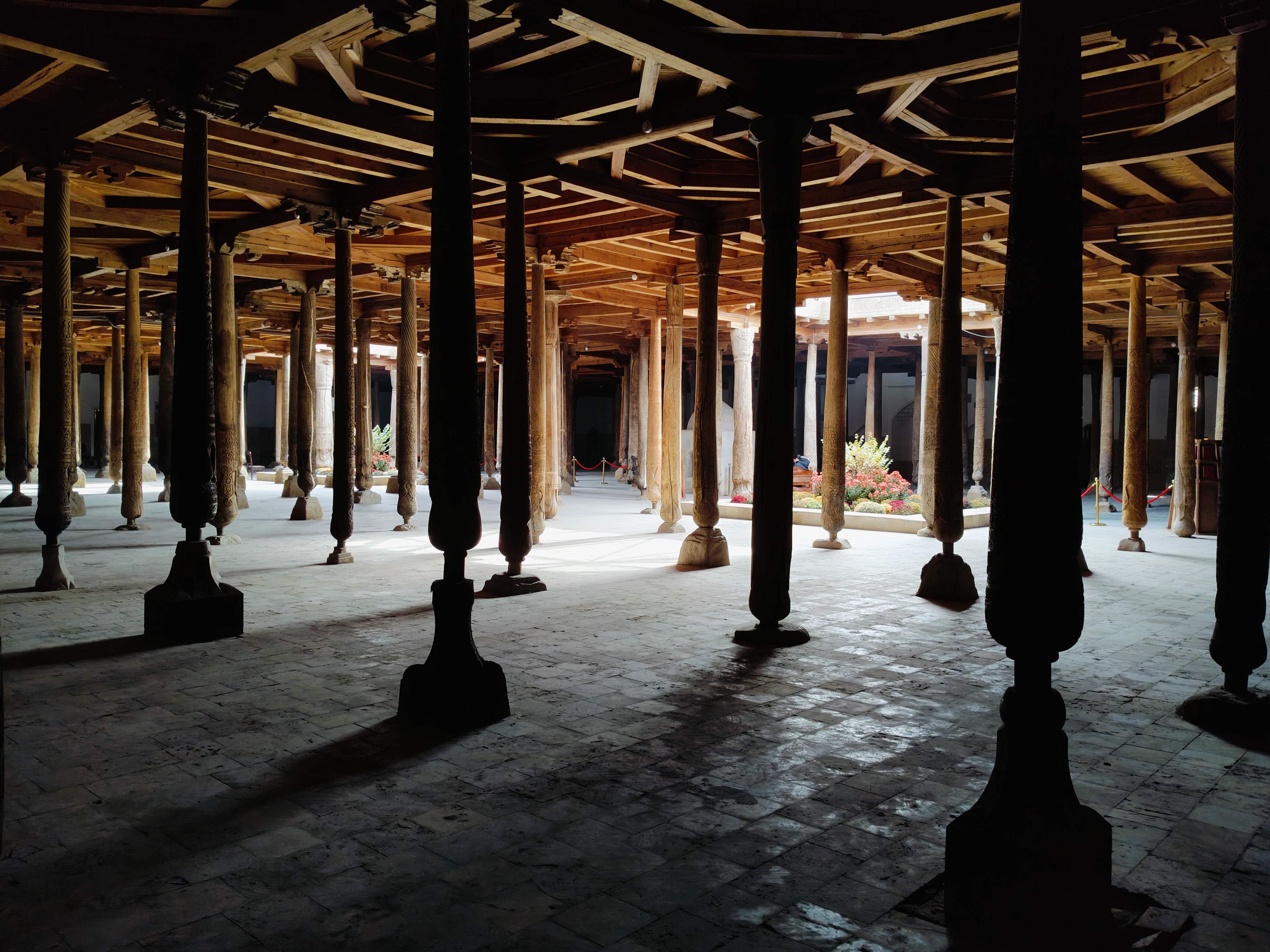 Historic wooden pillars inside Juma Mosque in Khiva - architectural marvel featuring 213 carved columns with 10 dating over 1000 years old, creating a forest-like prayer hall