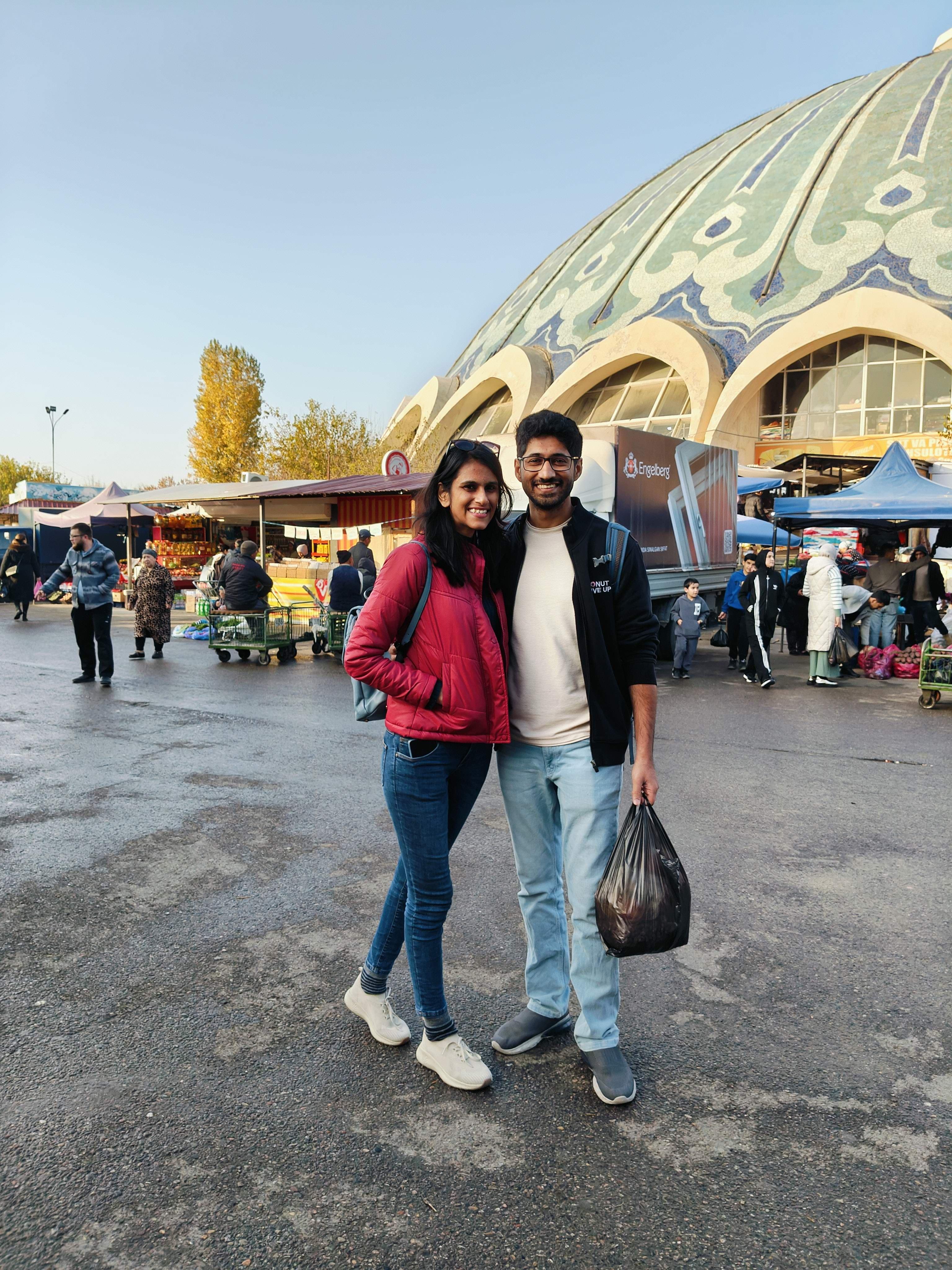Tourists with shopping bags outside Chorsu Bazaar in Tashkent - famous market experience where visitors can purchase authentic Uzbek dry fruits, spices, and traditional goods
