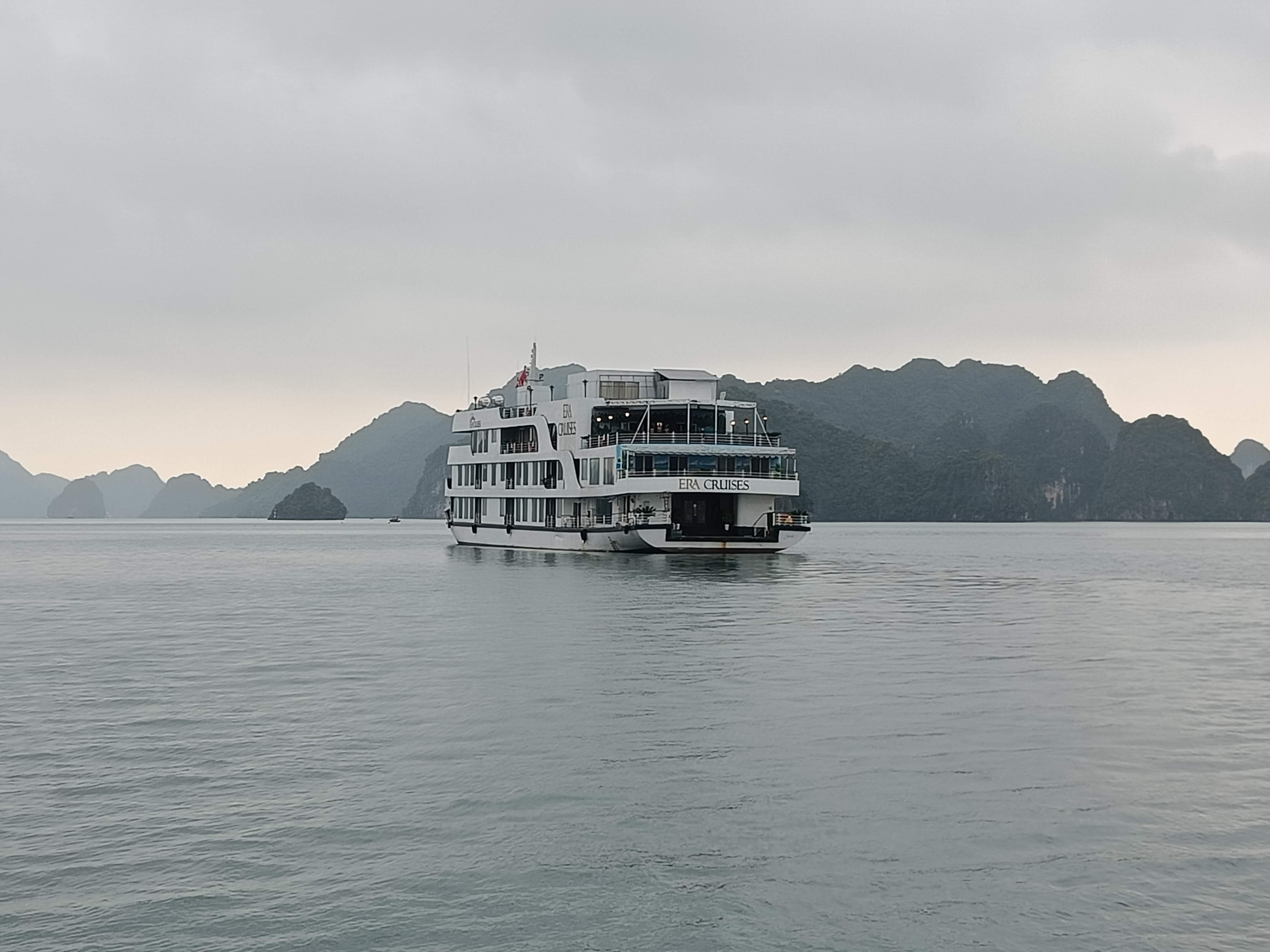 Luxury cruise ship navigating through Ha Long Bay's emerald waters and limestone islands in Vietnam