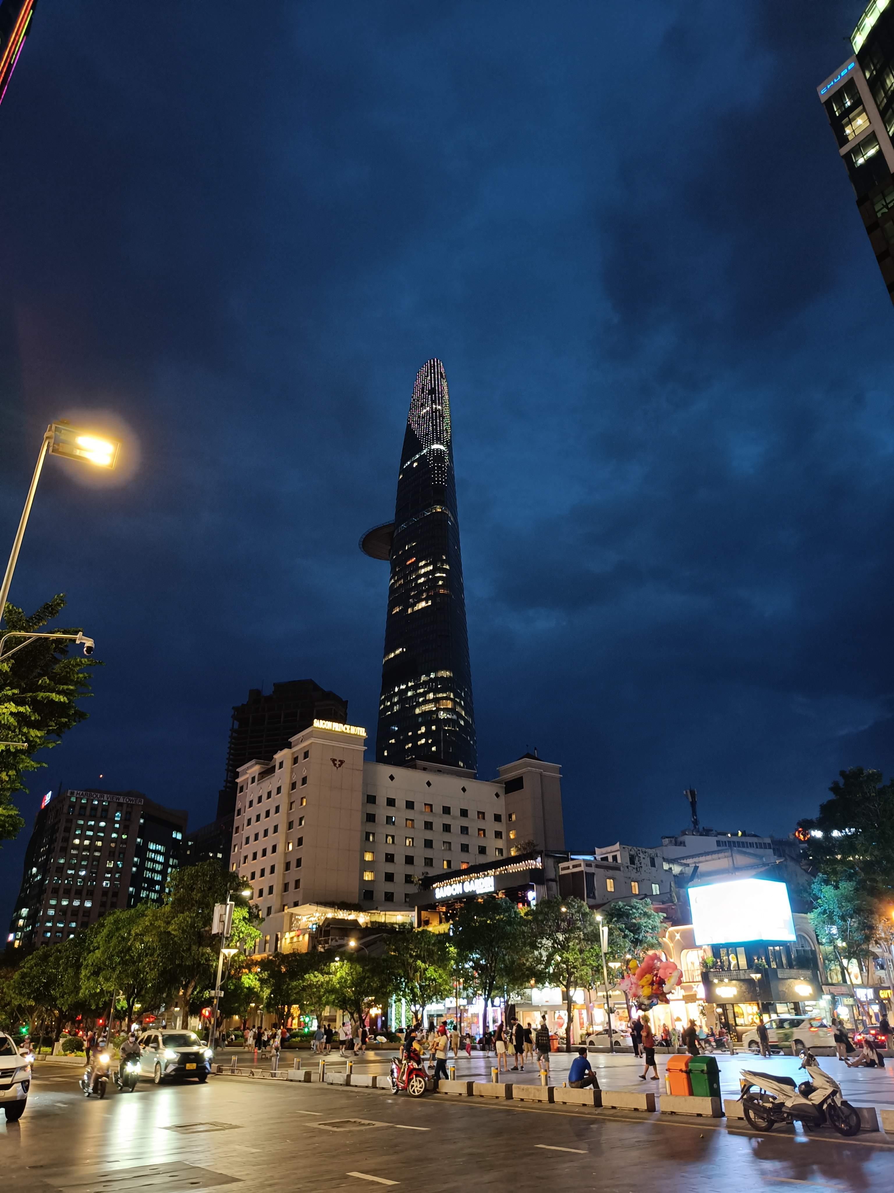 Bustling Ho Chi Minh Square at night with city hall building, visitors and illuminated landmarks in Vietnam